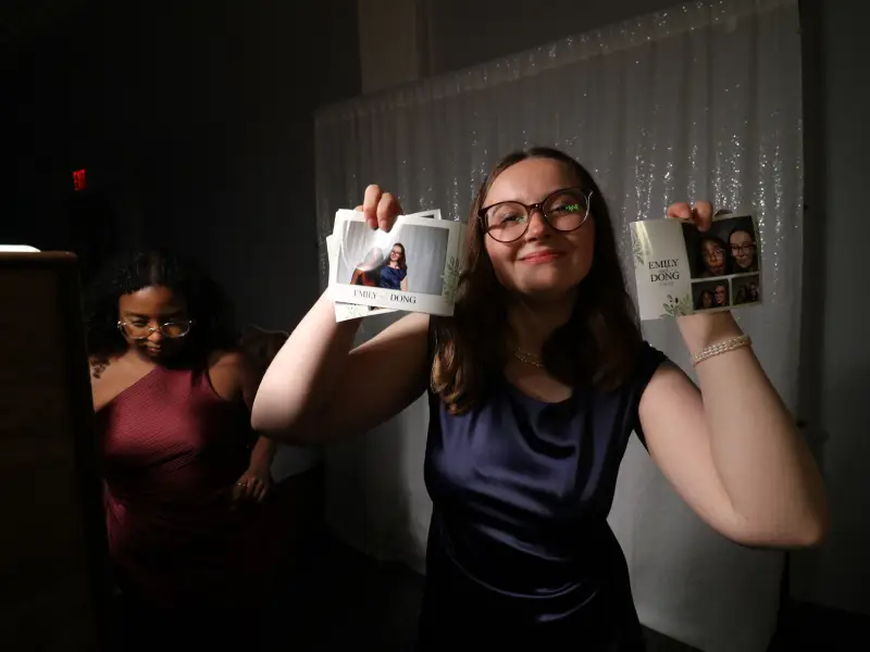Friends laughing together while using photo booth props